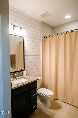 a bathroom with a sink a toilet a mirror and shower curtain