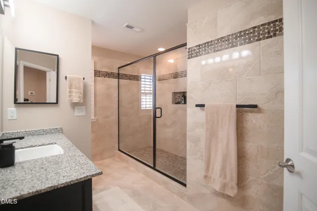 a bathroom with a granite countertop sink mirror and shower
