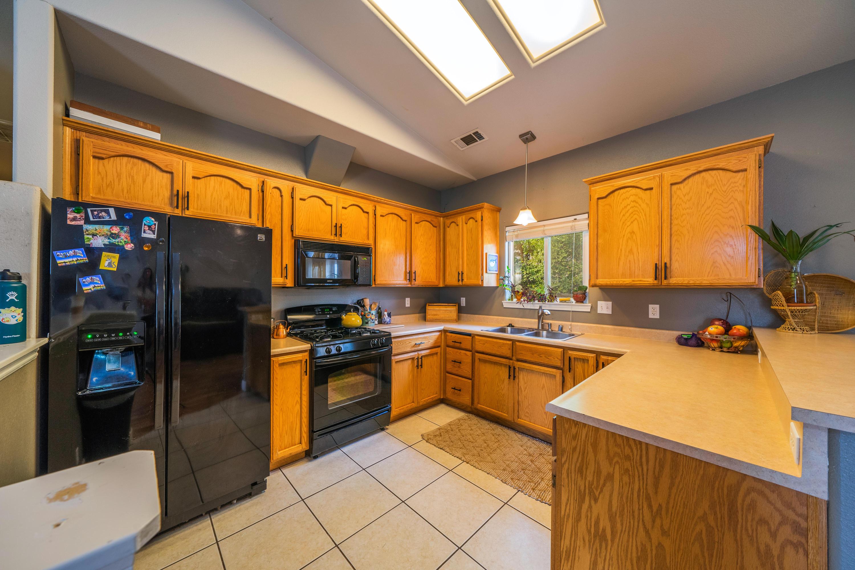 5484 Cedars Road Redding, CA 96001 - Photo 3 of 11 a kitchen with stainless steel appliances granite countertop a refrigerator a sink dishwasher a stove and a dining table with wooden floor