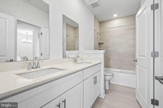 a bathroom with a double vanity sink toilet mirror and bathtub