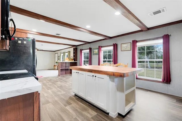a living room with stainless steel appliances granite countertop furniture wooden floor and a large window