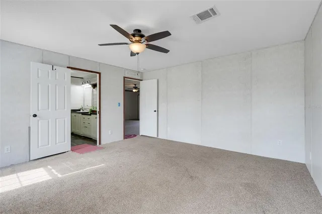 a view of a livingroom with a chandelier fan and windows