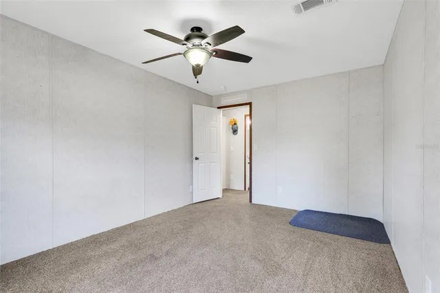 an empty room with a chandelier fan and a wooden floor