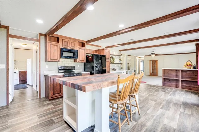 a kitchen with stainless steel appliances kitchen island granite countertop a table chairs and a refrigerator