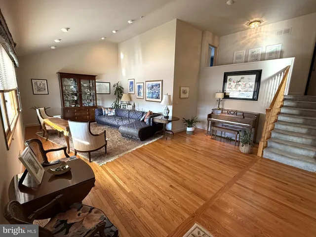 a living room with furniture a wooden floor and a piano