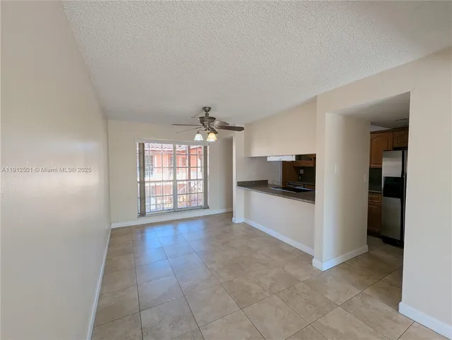 a view of a livingroom with a chandelier fan and kitchen view