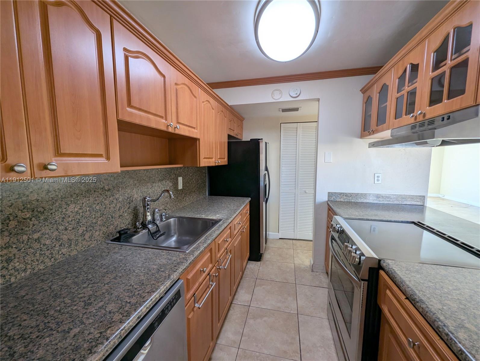 7230 Fairway Drive, Unit F4 Miami Lakes, FL 33014 - Photo 8 of 22 a kitchen with stainless steel appliances granite countertop a sink a stove and a wooden cabinets