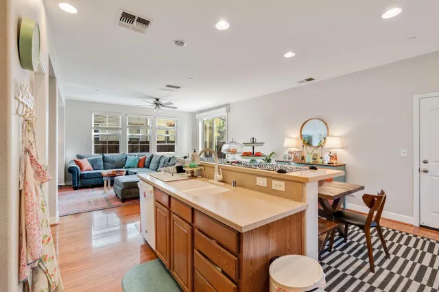 a open kitchen with stainless steel appliances a dining table and chairs with wooden floor