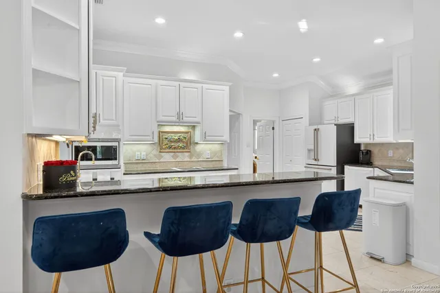 a kitchen with stainless steel appliances granite countertop a sink a stove a refrigerator cabinets and chairs