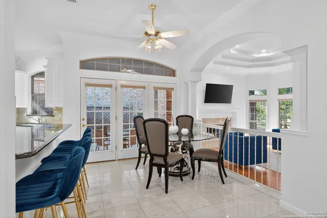 a view of a dining room with furniture a chandelier and large windows