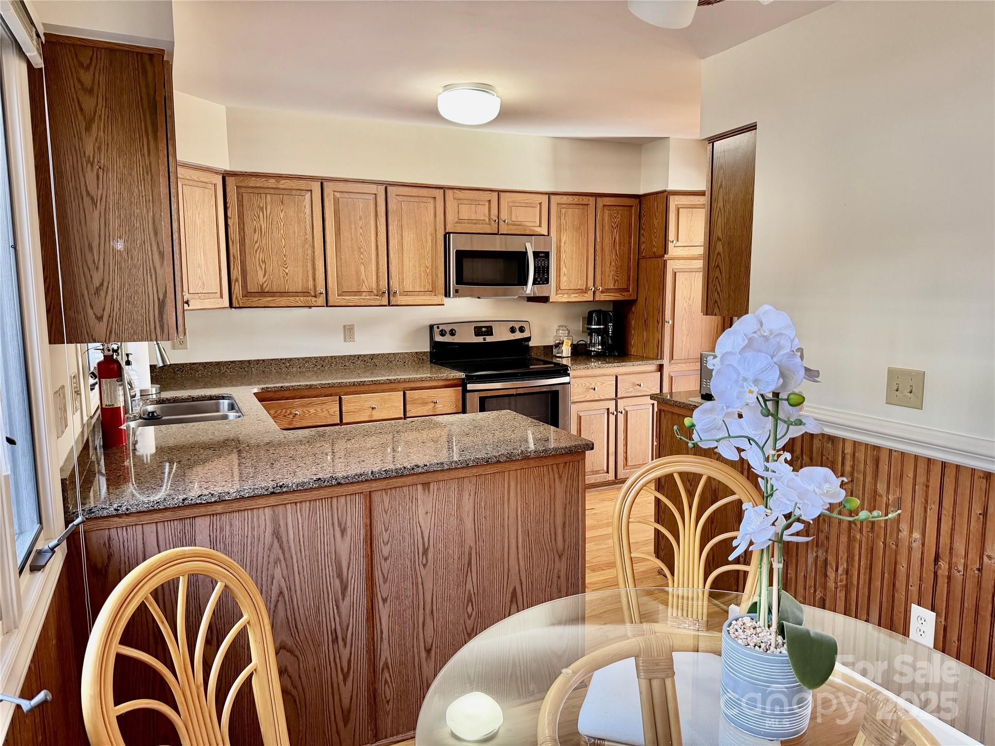 111 Burning Tree Lane, Unit C601 Flat Rock, NC 28731 - Photo 5 of 32 a kitchen with stainless steel appliances wooden cabinets a stove a sink and a microwave