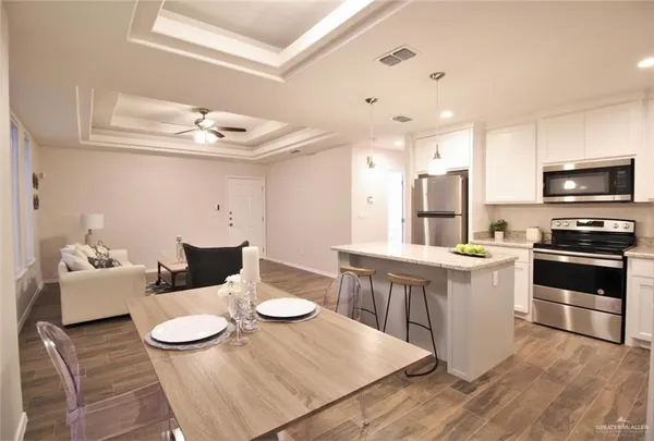 a kitchen with a dining table wooden floor and stainless steel appliances