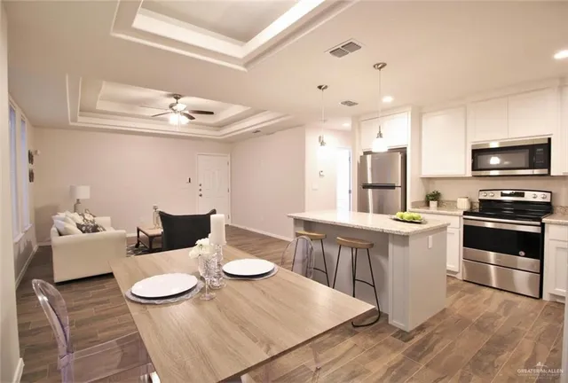 a kitchen with a dining table wooden floor and stainless steel appliances