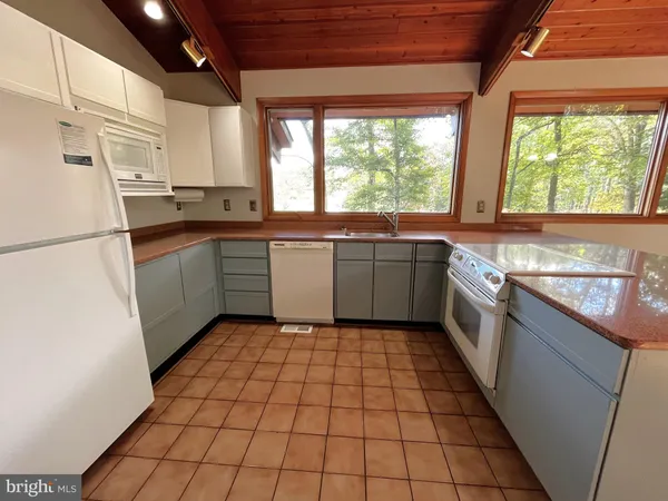 a kitchen with a sink a stove a refrigerator and white cabinets