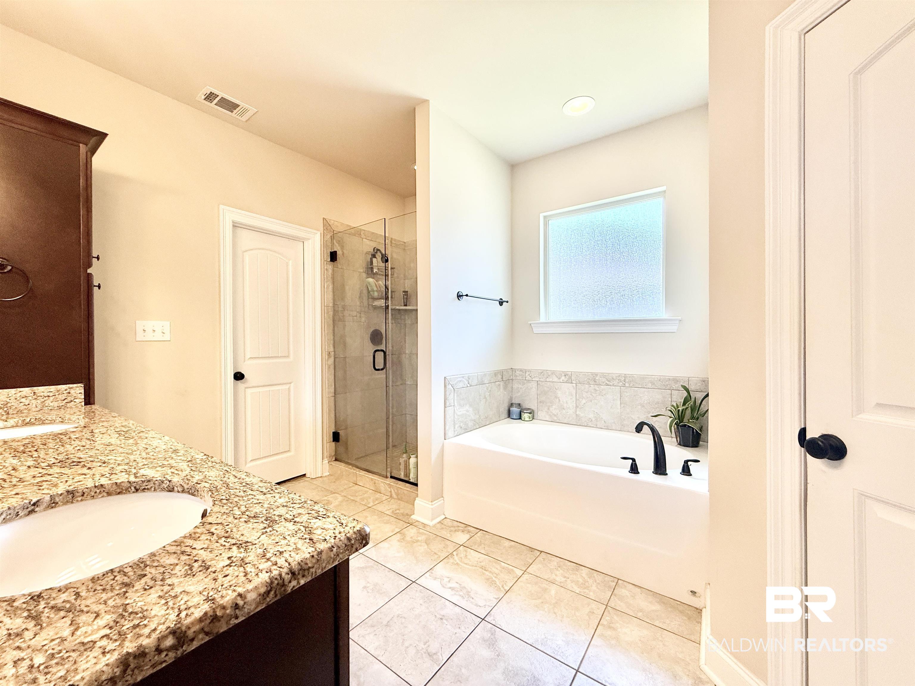 7011 Rocky Rd Loop Gulf Shores, AL 36542 - Photo 27 of 66 Full bath featuring a garden tub, double vanity, a shower stall, and light tile patterned flooring