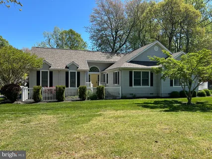 a front view of a house with a garden and trees