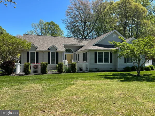 a front view of a house with a garden and trees
