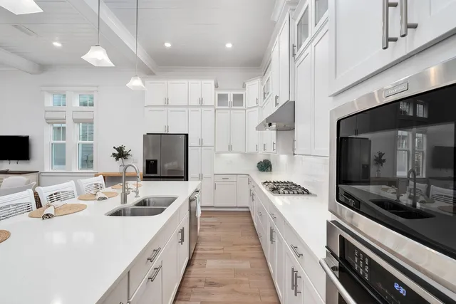 a large white kitchen with a sink and stove top oven