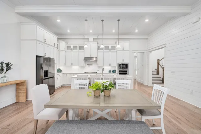 a kitchen with stainless steel appliances granite countertop a refrigerator a stove a sink a dining table and chairs