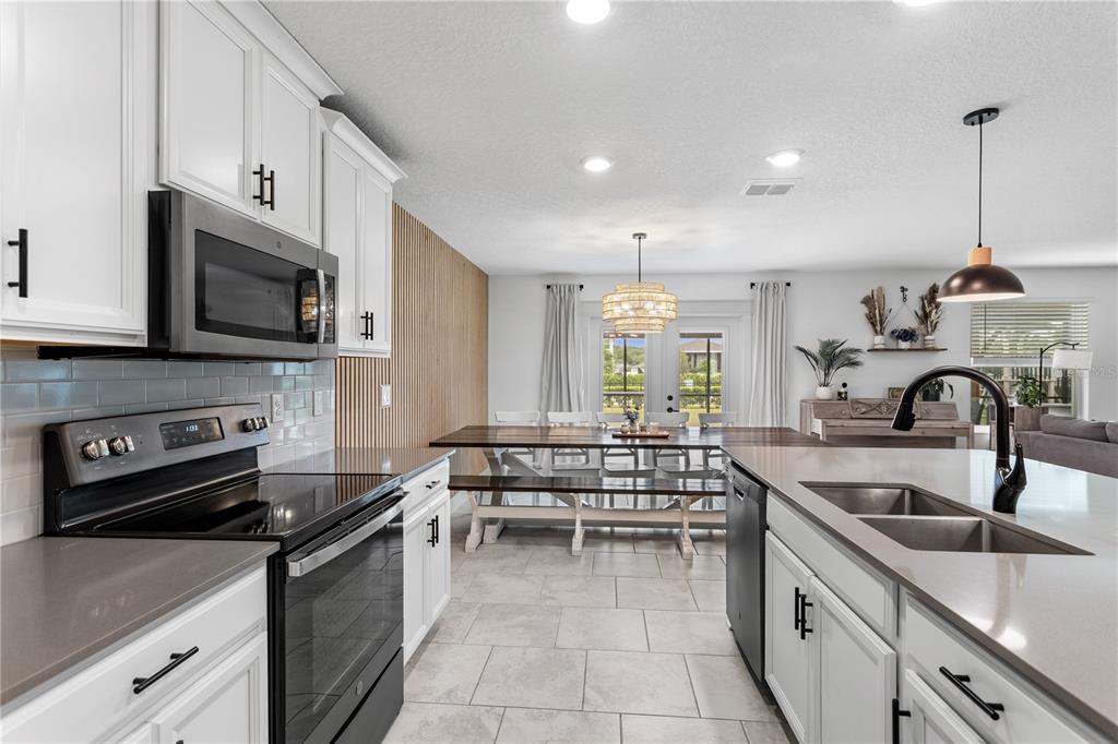 5693 Alenlon Way Mount Dora, FL 32757 - Photo 11 of 40 a kitchen with stainless steel appliances granite countertop a sink and a stove