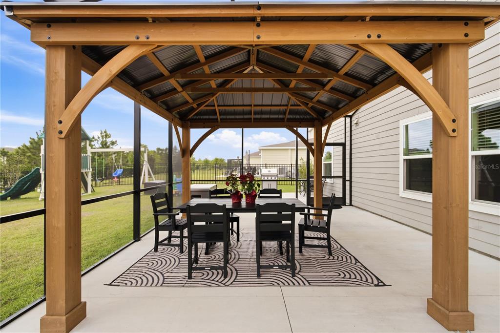 5693 Alenlon Way Mount Dora, FL 32757 - Photo 35 of 40 a view of a patio with table and chairs under an umbrella with a barbeque