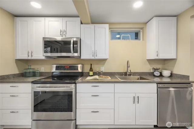 a kitchen with granite countertop white cabinets and stainless steel appliances