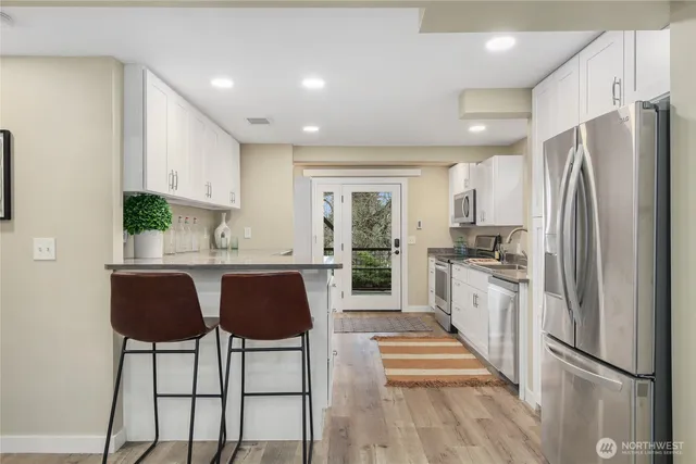 a kitchen with stainless steel appliances granite countertop a refrigerator and a stove top oven with wooden floor
