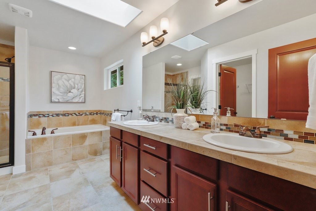 113 233rd Place Southeast Bothell, WA 98021 - Photo 22 of 39 a spacious bathroom with a granite countertop double vanity sink a mirror and a bathtub