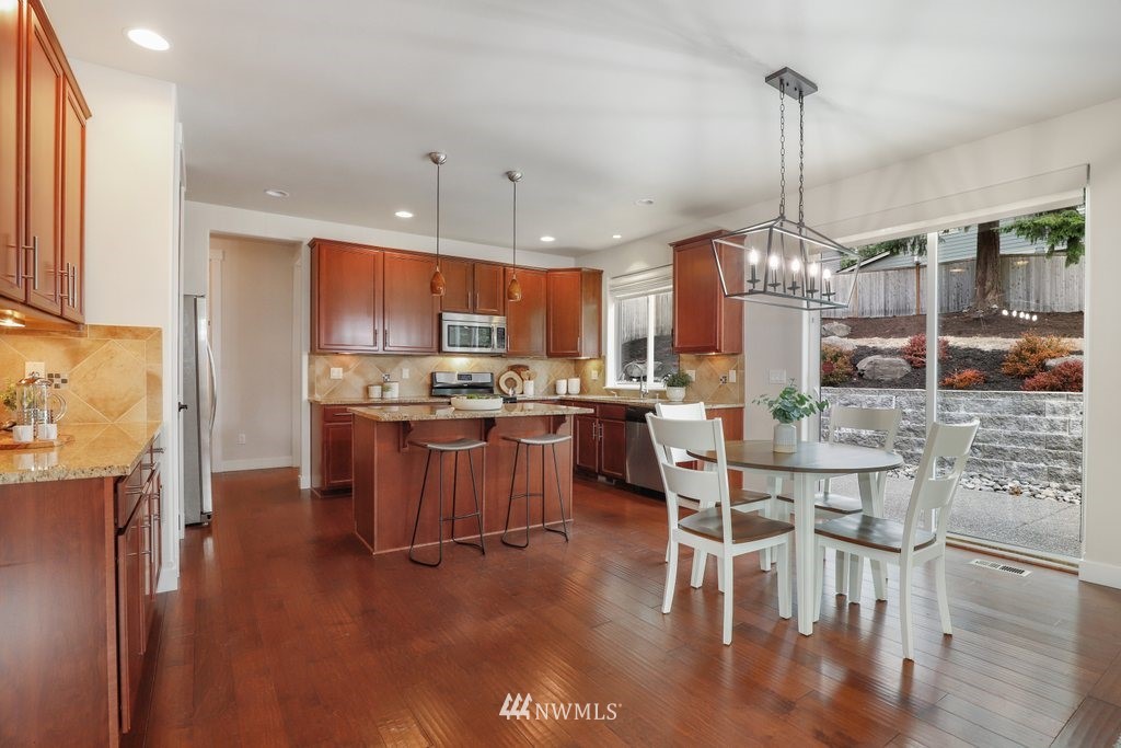 113 233rd Place Southeast Bothell, WA 98021 - Photo 6 of 39 a kitchen with stainless steel appliances kitchen island granite countertop a refrigerator a stove a kitchen island with a dining table and chairs