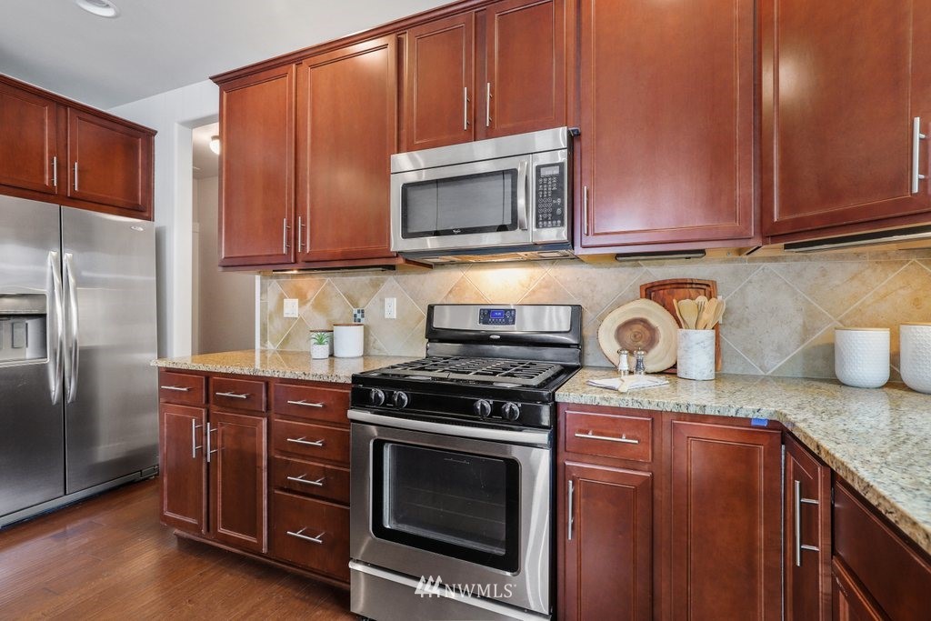 113 233rd Place Southeast Bothell, WA 98021 - Photo 9 of 39 a kitchen with granite countertop wooden cabinets and stainless steel appliances