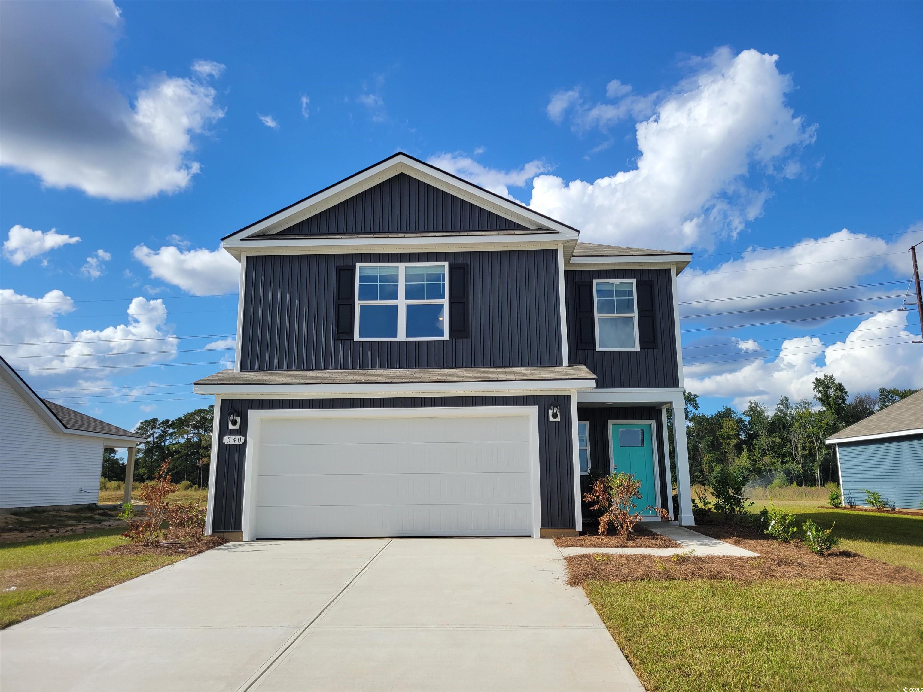 View of front of home featuring a garage, driveway, a front yard, and board and batten siding