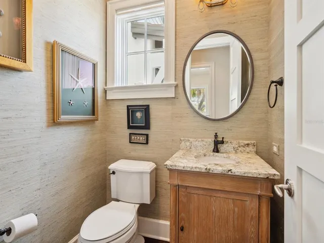 a bathroom with a granite countertop toilet a sink and a mirror