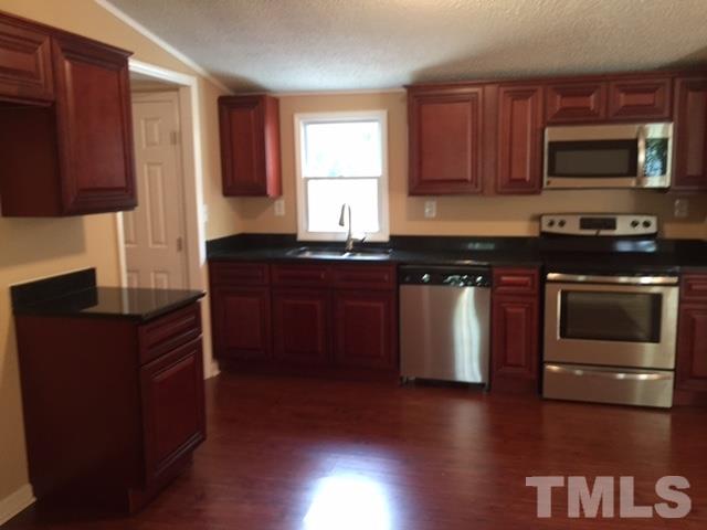 1390 Langdon Road Angier, NC 27501 - Photo 6 of 24 a kitchen with stainless steel appliances granite countertop a stove a sink and a microwave