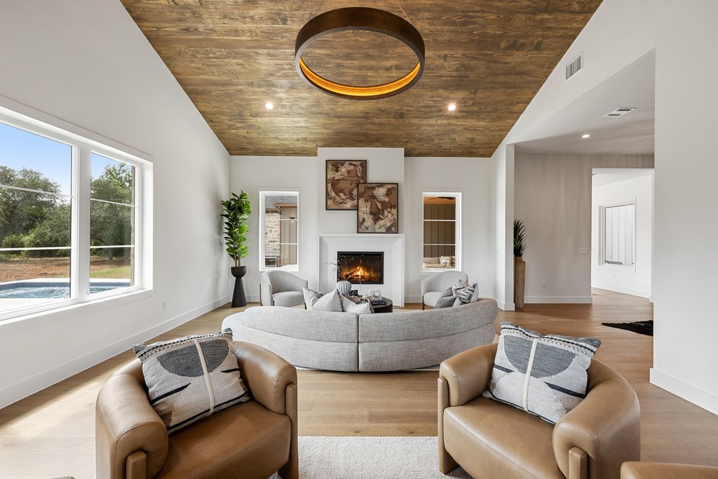 9207 Zyle Road Austin, TX 78737 - Photo 5 of 40 An inviting living room features a striking wood-paneled ceiling, a cozy fireplace, and direct views of a private pool.
