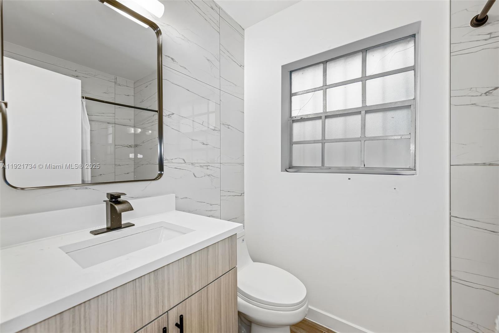 23 Southwest 8th Street Hallandale Beach, FL 33009 - Photo 14 of 18 a bathroom with a sink toilet a mirror and shower