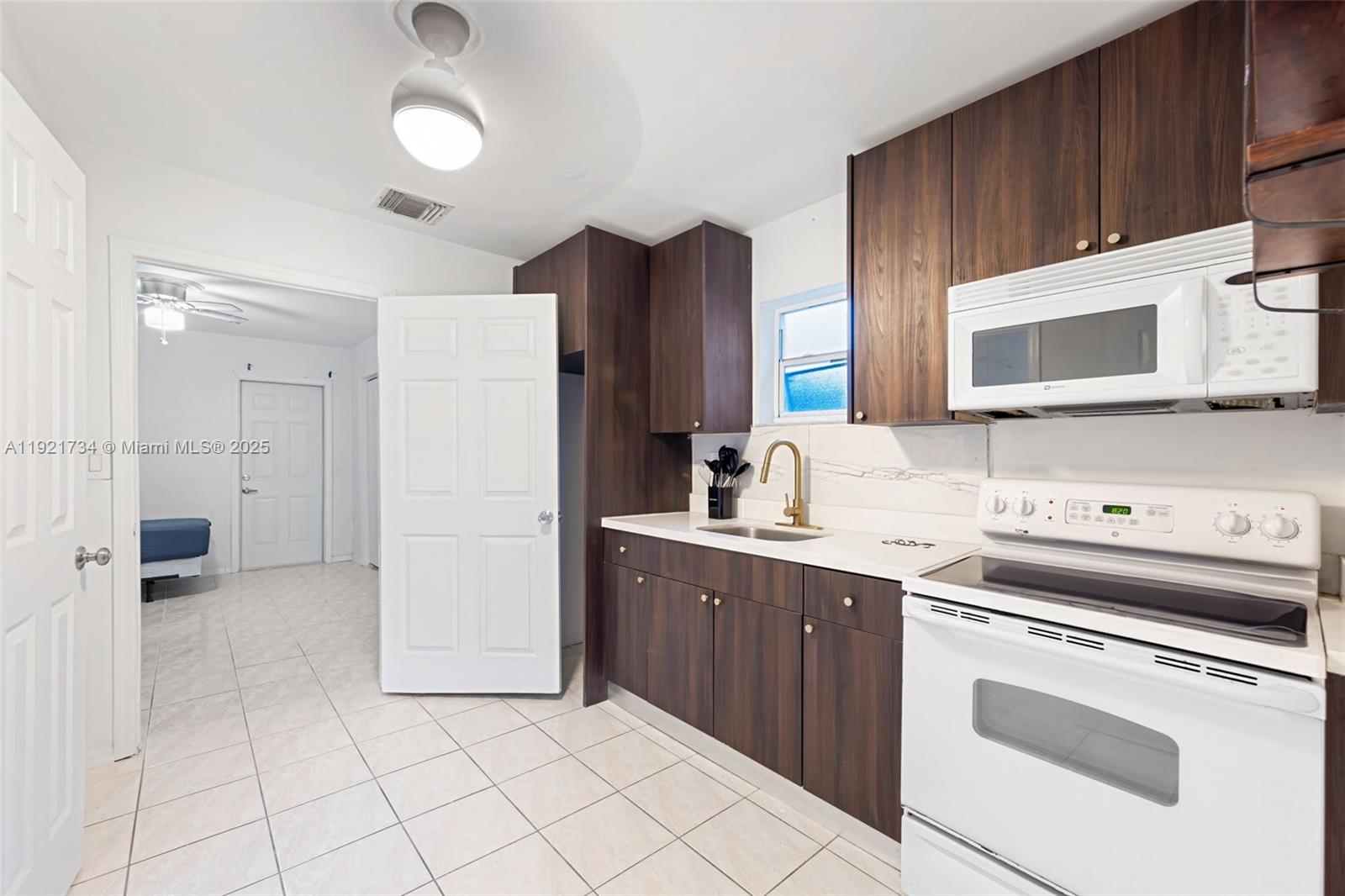 23 Southwest 8th Street Hallandale Beach, FL 33009 - Photo 7 of 18 a kitchen with stainless steel appliances a stove microwave and cabinets