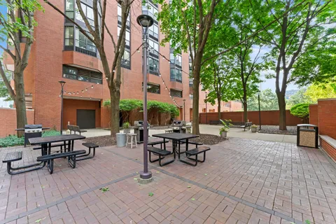 a view of a patio with dining table and chairs under an umbrella with large trees