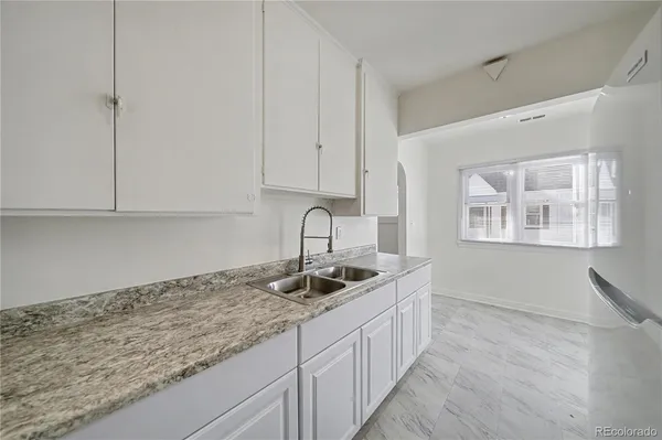 a kitchen with granite countertop white cabinets and sink