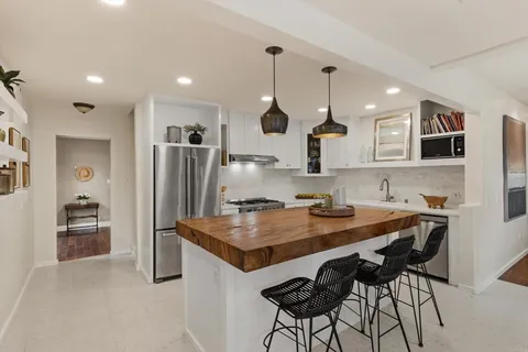 a kitchen with stainless steel appliances granite countertop a stove top oven a refrigerator a sink and a island