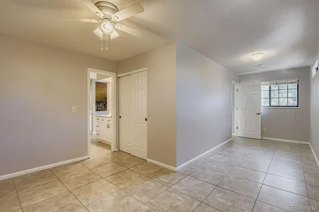 a view of an empty room with window and chandelier fan