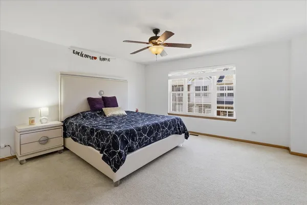 a bedroom with a large bed and a chandelier fan