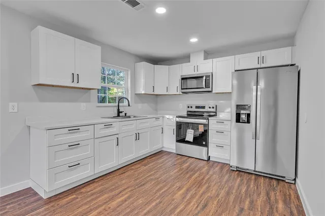a kitchen with white cabinets and stainless steel appliances