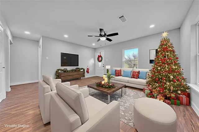 a living room with furniture a flat screen tv and a christmas tree
