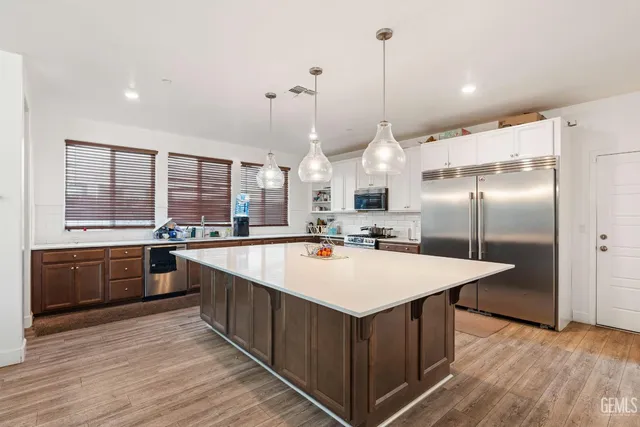 a large kitchen with kitchen island a large island a sink a stove and wooden floor