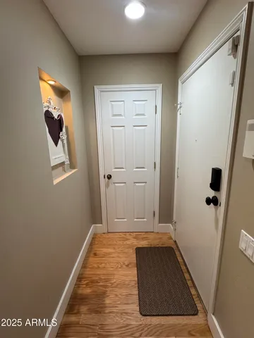 a view of a hallway with wooden floor and a bathroom
