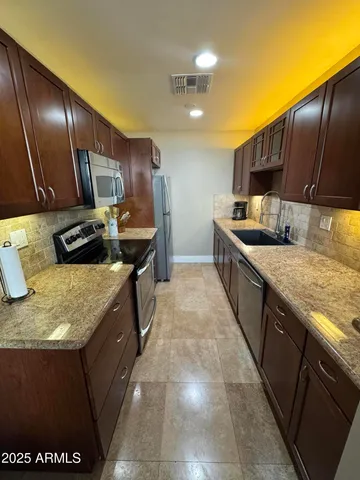 a kitchen with stainless steel appliances granite countertop sink stove refrigerator and cabinets