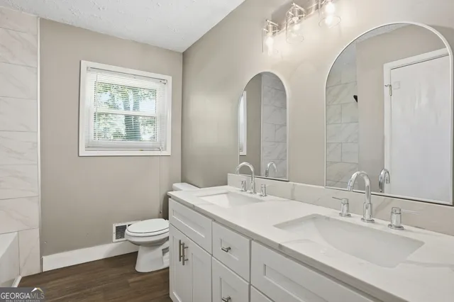 a bathroom with a double vanity sink toilet and a mirror