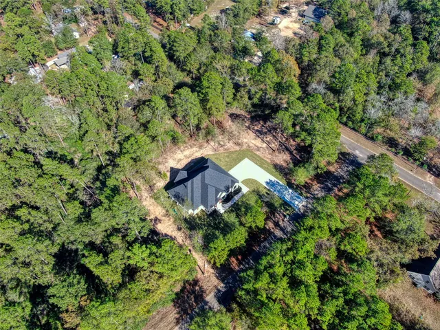 an aerial view of residential house with outdoor space and trees all around