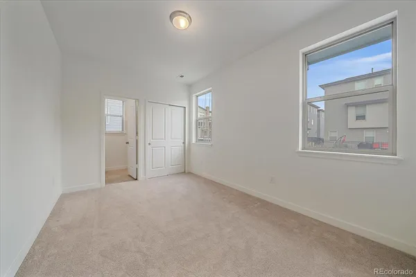 a view of an empty room with window and closet area