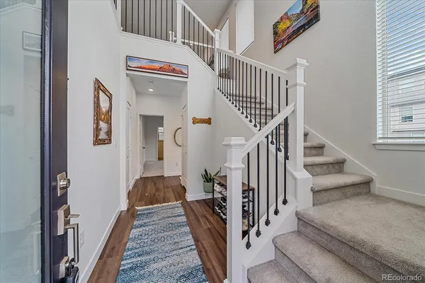a view of a hallway to a livingroom with wooden floor and stairs